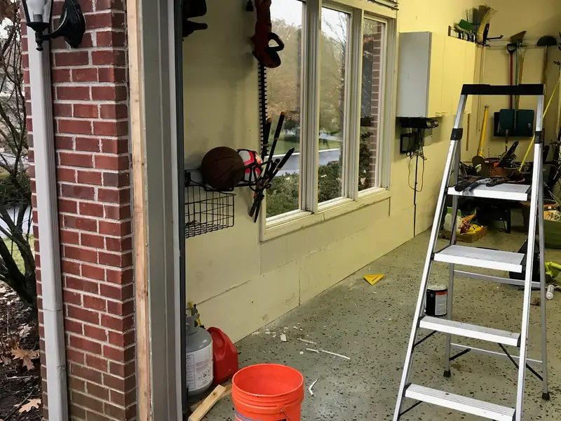 Garage interior with a ladder set up beside a window being worked on