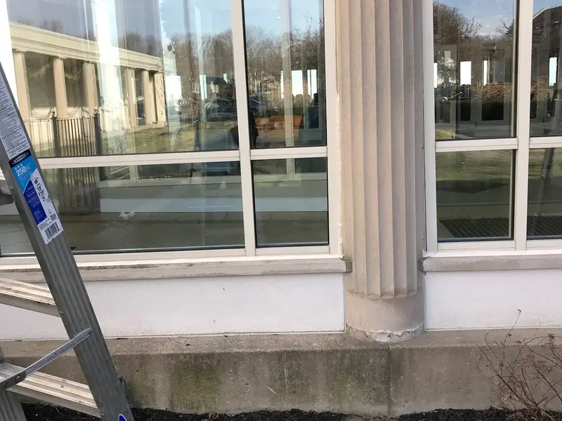 Tall commercial windows beside a column, ladder in place for service