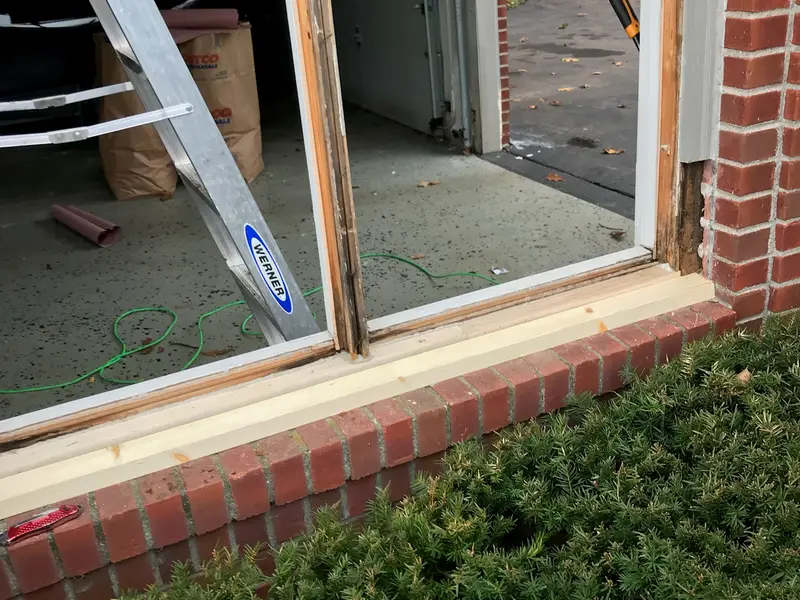 Window opening in a brick wall with the glass removed and a ladder inside