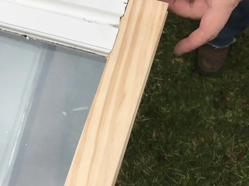 Hands fitting a new wood strip onto a window sash