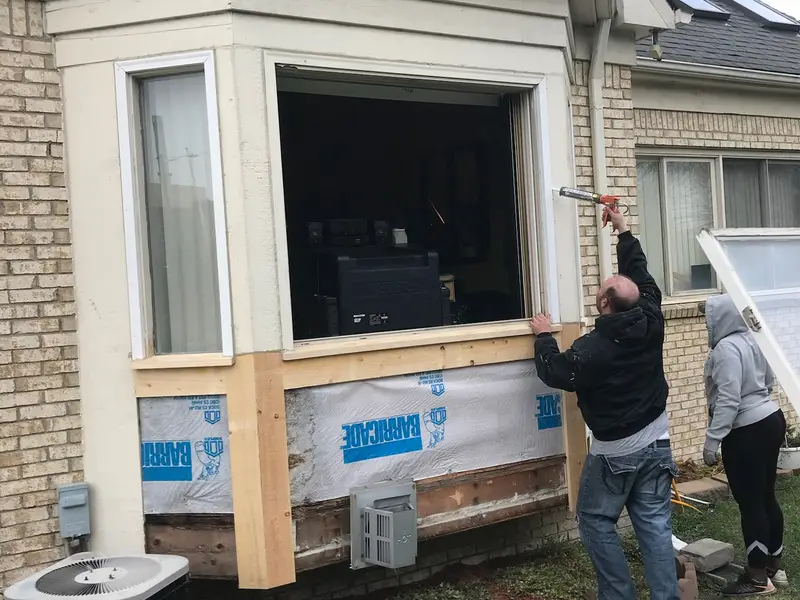 Crew installing a bay window on a brick home